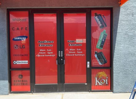 Red storefront with various brand logos on glass doors and windows.