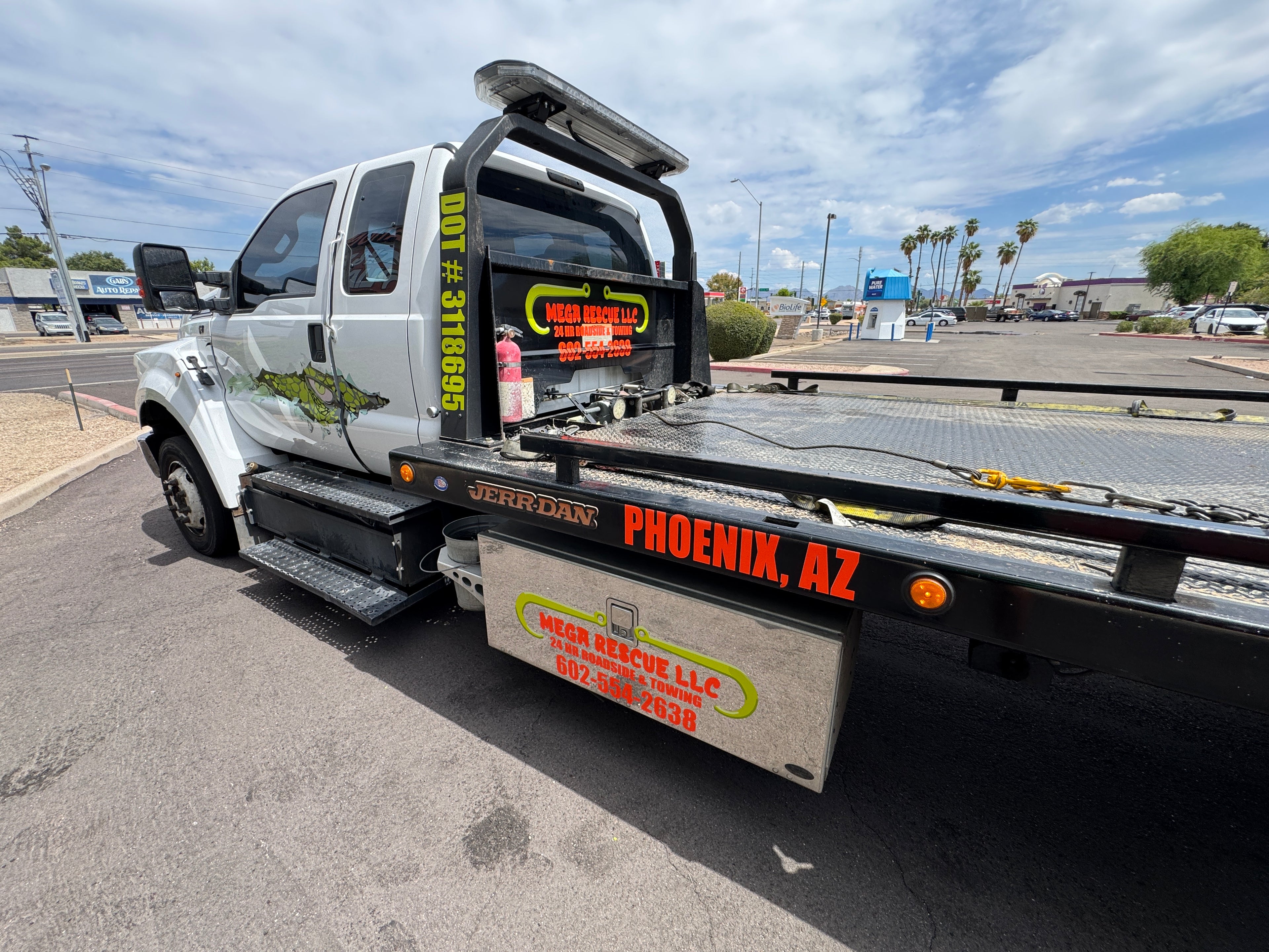 Tow truck with visible branding and contact information in a parking lot.